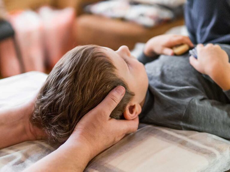 A person rolling to their side in bed and using their arms to help sit up slowly in a softly lit bedroom.