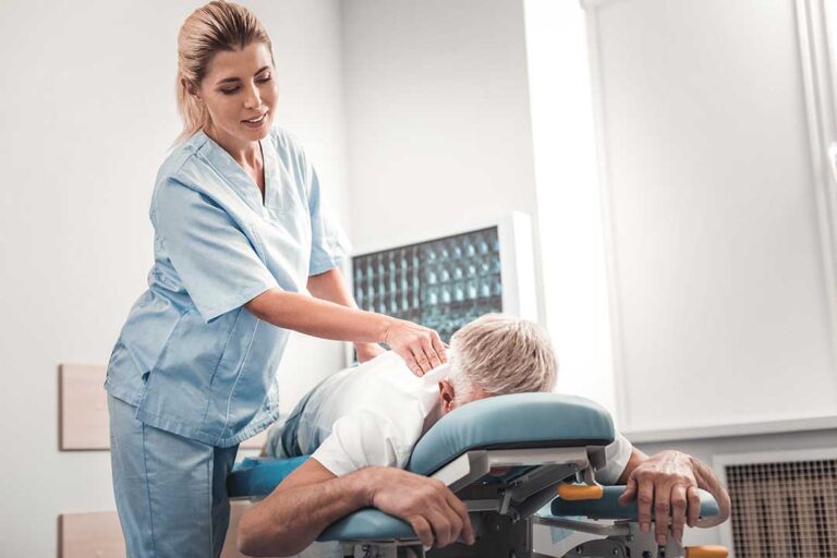 A chiropractor gently adjusting an adult patient's spine in a bright clinical setting.