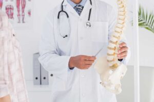 Person standing and stretching beside a window after receiving care for back stiffness.