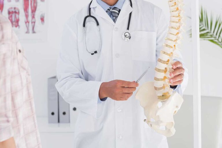Person standing and stretching beside a window after receiving care for back stiffness.