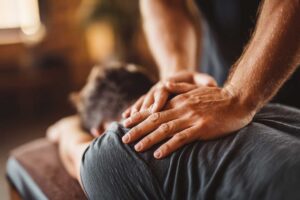 A middle-aged person gently stretching their back in a bright living room with natural daylight.